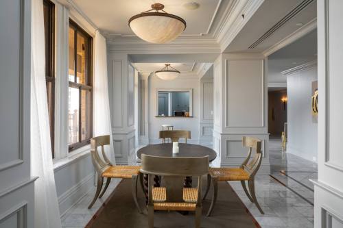 A modern dining area featuring a round table, four chairs, and large windows with soft curtains.