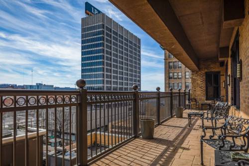 View from a balcony with metal railings, overlooking a cityscape and a tall building under a blue sky.