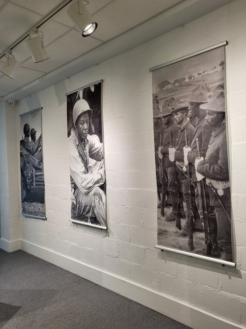 Three large black-and-white photographs of soldiers displayed on a gallery wall, showcasing military history.