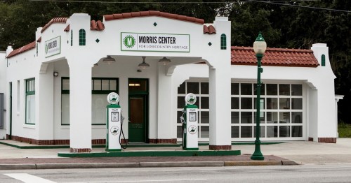 Historic building with a white facade, green accents, and vintage gas pumps, housing the Morris Center for Lowcountry Heritage.