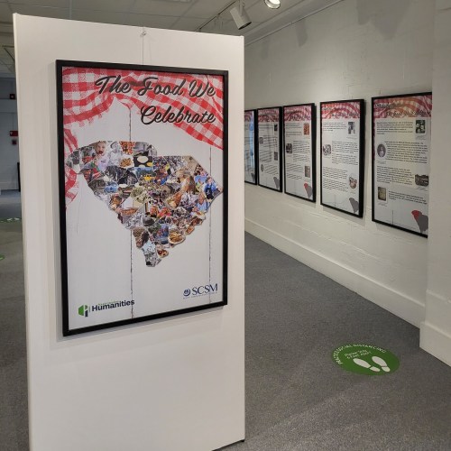Exhibit titled "The Food We Celebrate" featuring a collage of food images, with informational panels in the background.