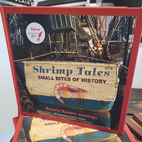 A signed book titled "Shrimp Tates: Small Bites of History" featuring a shrimp graphic and a colorful boat background.