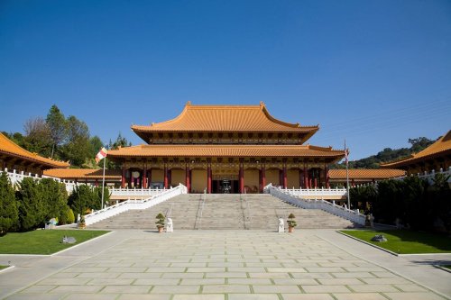 A grand temple with a traditional Asian architectural style, featuring a large staircase and clear blue sky.
