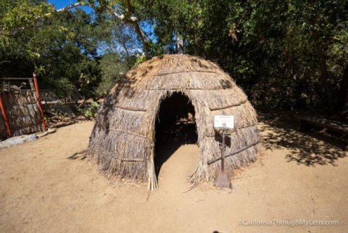 A traditional straw hut with a rounded shape, set in a natural outdoor environment.