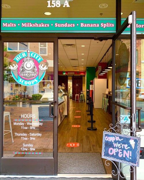 Entrance to Hub City Scoops ice cream shop, featuring hours and a sign that says "Come in, we're open!"