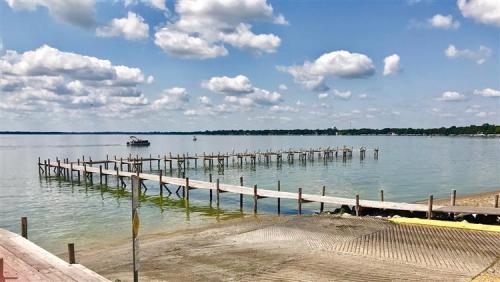 A serene lake view with a wooden pier extending into the water, under a sky filled with fluffy clouds.