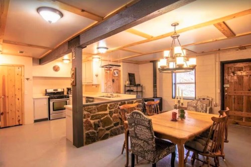 Cozy kitchen and dining area with wooden beams, stone accents, and a rustic table set for a meal.