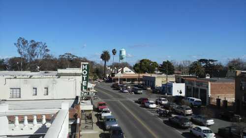 A view of a small town with a hotel sign, palm trees, and a water tower under a clear blue sky.