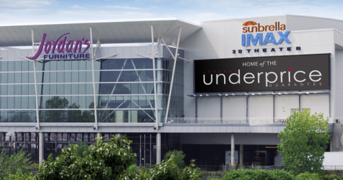 Exterior view of Jordan's Furniture with a large sign for the Sunbrella IMAX theater and the Underprice Guarantee.