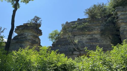 Rock formations surrounded by lush greenery under a clear blue sky.