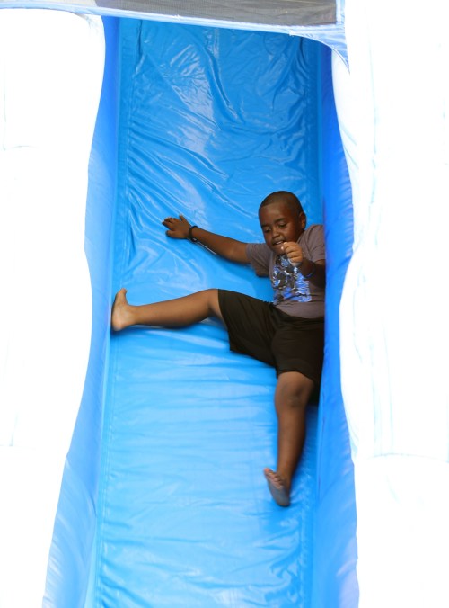 A child slides down a blue inflatable slide, enjoying a fun moment at a play area.
