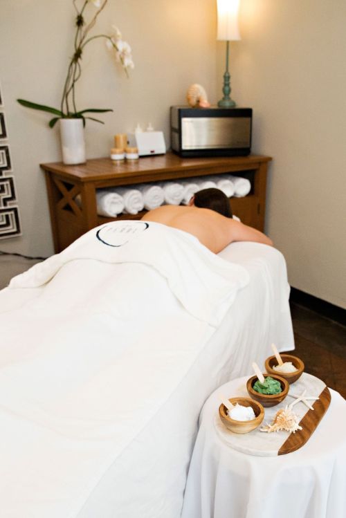 A person receiving a massage on a spa table, with towels and spa products in the background. Relaxing ambiance.
