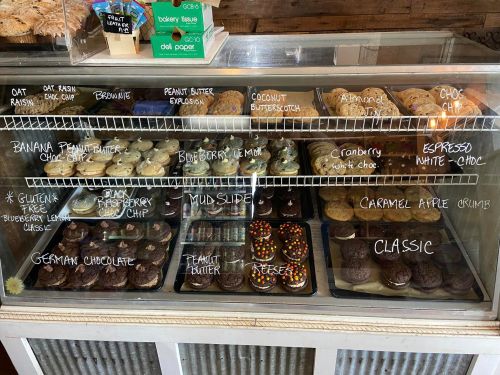A display case filled with various cookies, labeled with flavors like oatmeal, chocolate, and peanut butter.