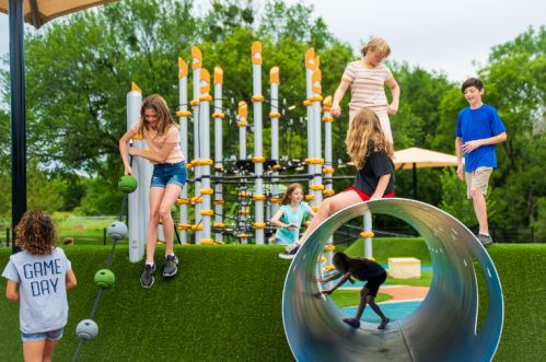 Children playing on a colorful playground, climbing structures, and sliding down a tube on a sunny day.