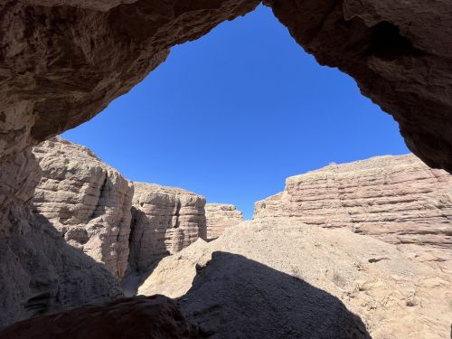 View of rugged canyon walls framed by a rocky arch, with a clear blue sky above.