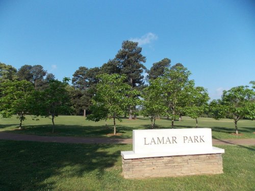 Sign for Lamar Park in a green area with trees and a clear blue sky.