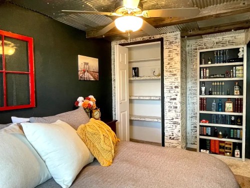Cozy bedroom with a bed, decorative pillows, a bookshelf, and a vintage window frame on the wall.