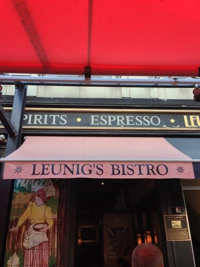A view of Leunig's Bistro with a pink awning and a sign above reading "Spirits Espresso" in a vibrant outdoor setting.