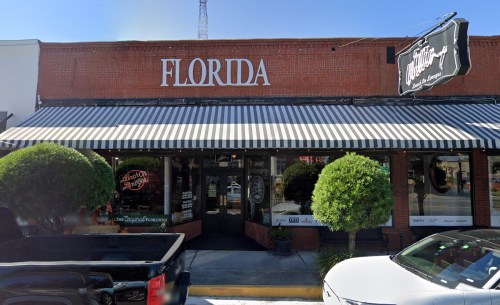 Exterior of a restaurant with a striped awning, sign reading "Florida," and potted plants on either side of the entrance.