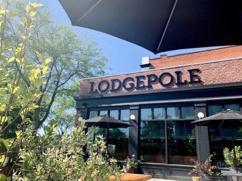 Exterior of a restaurant named "Lodgepole," featuring outdoor seating and umbrellas under a clear blue sky.