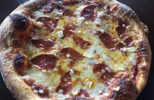 A freshly baked pepperoni pizza with melted cheese and a golden crust, topped with herbs and spices.
