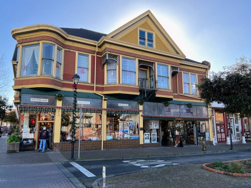 Historic building with colorful exterior, large windows, and festive decorations, located on a street with pedestrians.