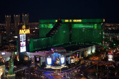 The MGM Grand hotel illuminated at night, showcasing vibrant green lights and nearby attractions in Las Vegas.
