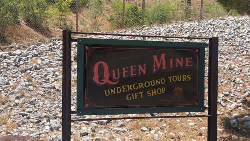 Sign for Queen Mine featuring "Underground Tours" and "Gift Shop," set against a rocky landscape.