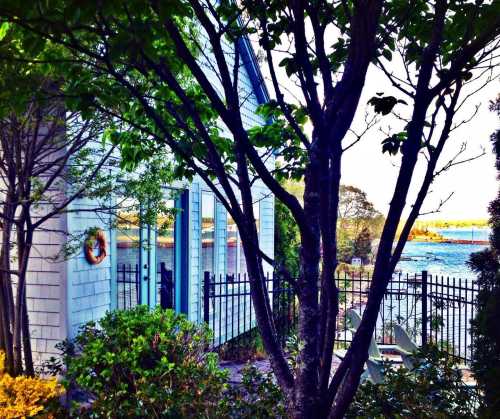 A coastal house surrounded by greenery, with a view of the water in the background and a decorative wreath on the wall.