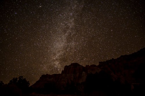 A starry night sky filled with countless stars above a dark silhouette of mountains.