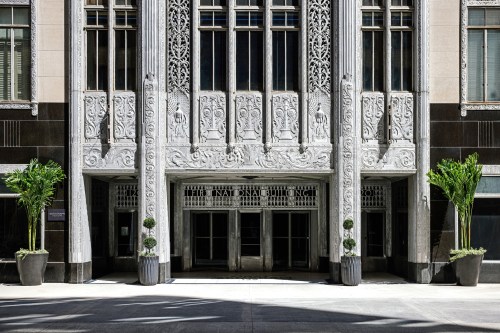 Art Deco entrance of the International Building, featuring intricate carvings and potted plants on either side.