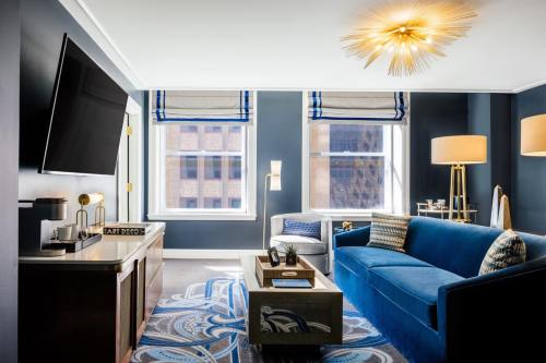 Modern hotel room featuring a blue sofa, stylish decor, large windows, and a flat-screen TV.