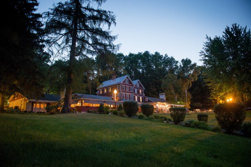 A charming lodge illuminated at dusk, surrounded by trees and lush greenery.