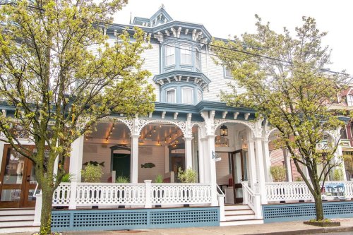 Victorian-style building with ornate architecture, surrounded by trees and a welcoming porch.
