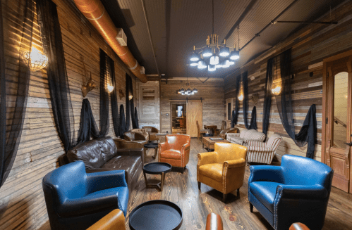 Cozy lounge with leather and upholstered seating, wooden walls, and stylish lighting, creating a warm atmosphere.