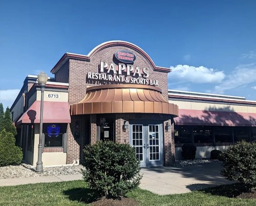 Exterior of Pappas Restaurant & Sports Bar, featuring a brick facade and a copper awning under a clear blue sky.