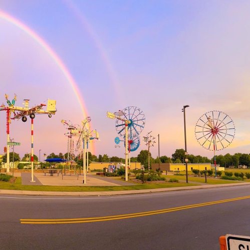 A colorful amusement park scene with a rainbow, whimsical structures, and a vibrant sky at sunset.