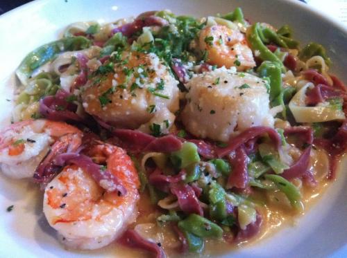 A plate of pasta with shrimp and scallops, garnished with parsley in a creamy sauce.