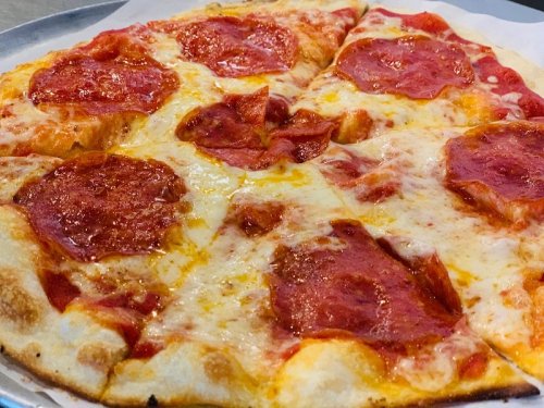 A close-up of a pepperoni pizza with melted cheese on a golden crust, served on a round tray.