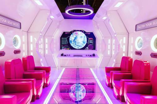 Futuristic spaceship interior with pink seats, a large screen displaying a globe, and glowing circular lights.