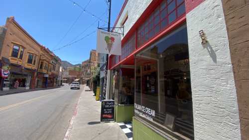 A colorful street scene featuring an ice cream shop with a sign, surrounded by historic buildings and a clear blue sky.