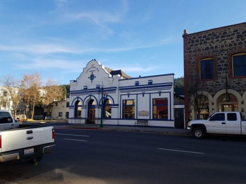 Historic blue and white building with arched windows, set against a clear sky in a small town.