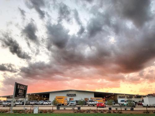 A commercial building with trucks parked outside, under a dramatic sky with clouds at sunset.