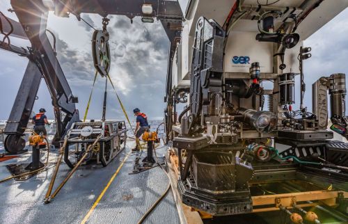A marine research vessel deck with equipment and crew preparing for underwater exploration.