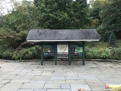 Information kiosk in a park, surrounded by greenery, with maps and details about the landscape.