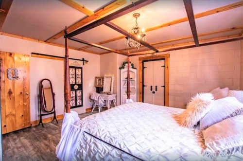 Cozy bedroom featuring a four-poster bed, wooden accents, and elegant decor with a mirror and vintage furniture.