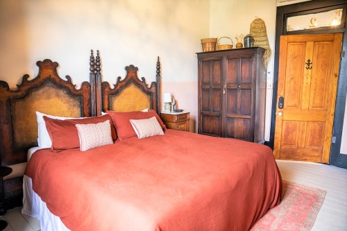 Cozy bedroom featuring a large orange bedspread, wooden furniture, and a warm, inviting atmosphere.