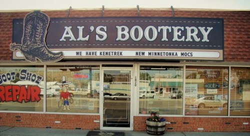 Sign for Al's Bootery featuring cowboy boots, shoe repair services, and advertisements for Kenetrek and Minnetonka moccasins.