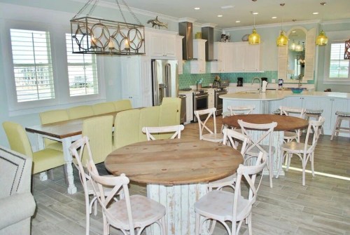 Bright, modern kitchen and dining area with wooden tables, yellow chairs, and stylish light fixtures.