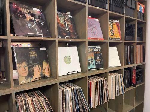 A wooden shelf filled with various vinyl records, showcasing album covers and neatly organized rows.